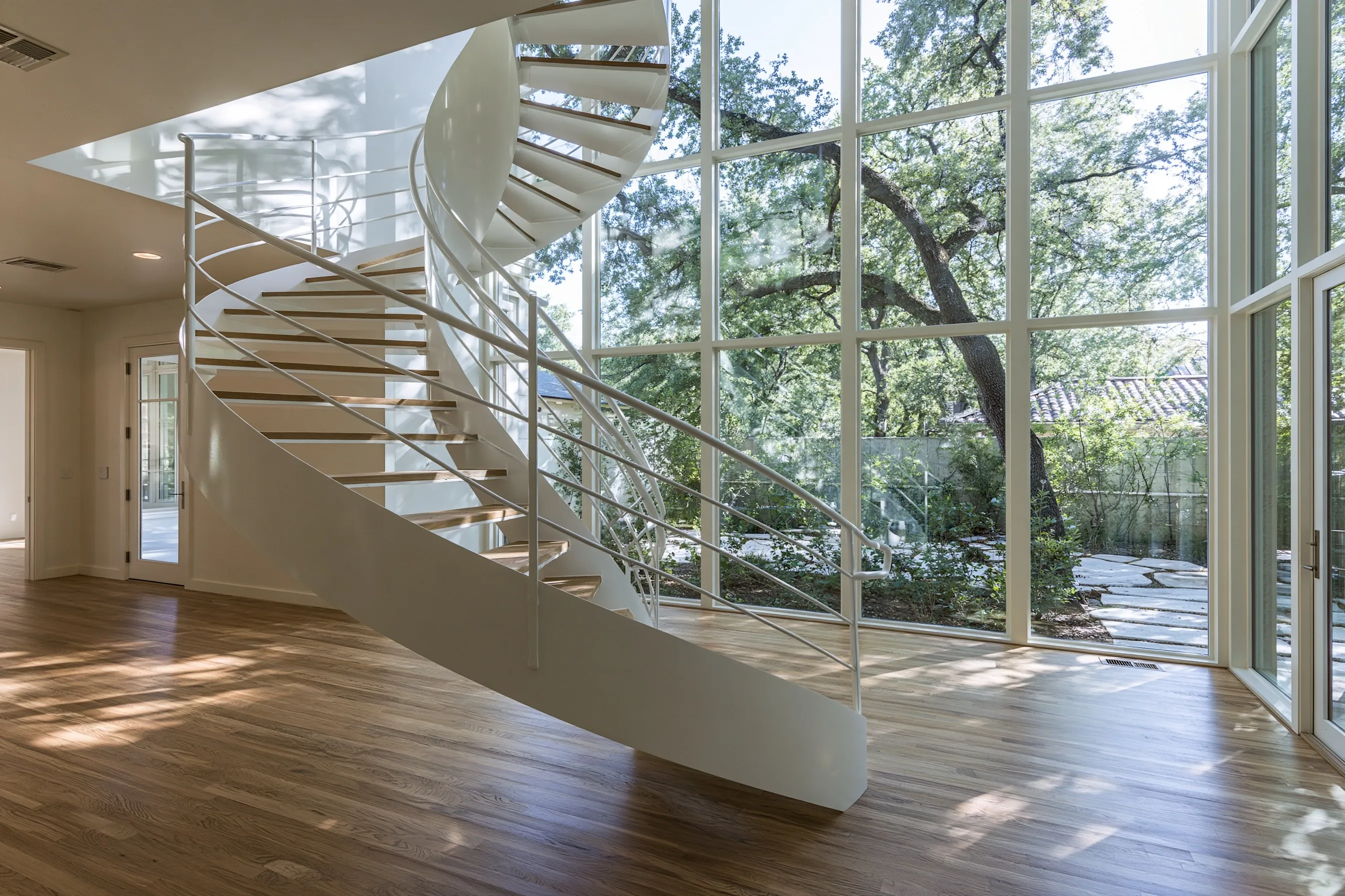 Freestanding helical staircase with no center column, smooth curved stringers and wood treads in a large entry hall